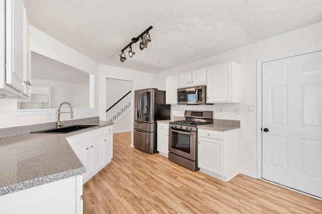 1186 Hawthorn Ln, Grayson, GA 30017 - kitchen featuring appliances with stainless steel finishes, a sink, a textured ceiling, light wood-style flooring, and white cabinetry
