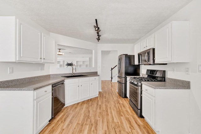 1186 Hawthorn Ln, Grayson, GA 30017 - kitchen with appliances with stainless steel finishes, a sink, light wood-type flooring, white cabinetry, and a textured ceiling