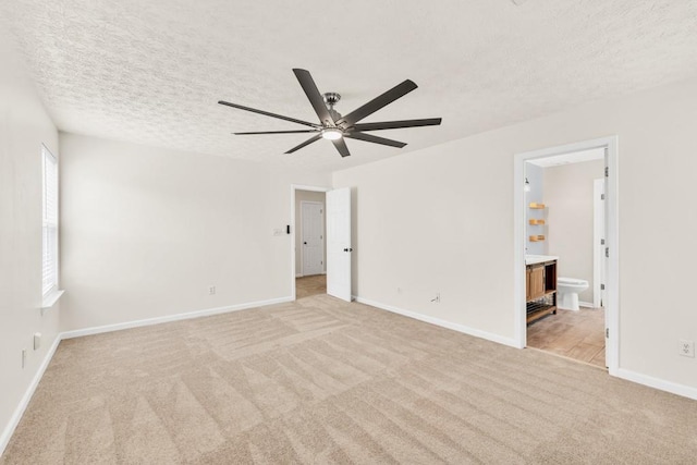 1186 Hawthorn Ln, Grayson, GA 30017 - unfurnished bedroom with light colored carpet, a textured ceiling, baseboards, connected bathroom, and ceiling fan
