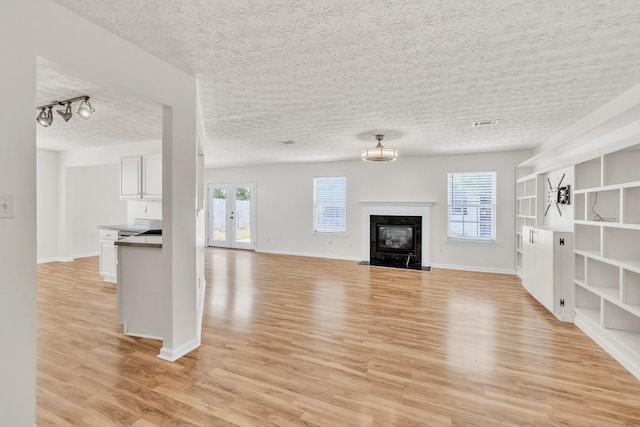 1186 Hawthorn Ln, Grayson, GA 30017 - unfurnished living room featuring light wood-type flooring, a textured ceiling, baseboards, and a premium fireplace