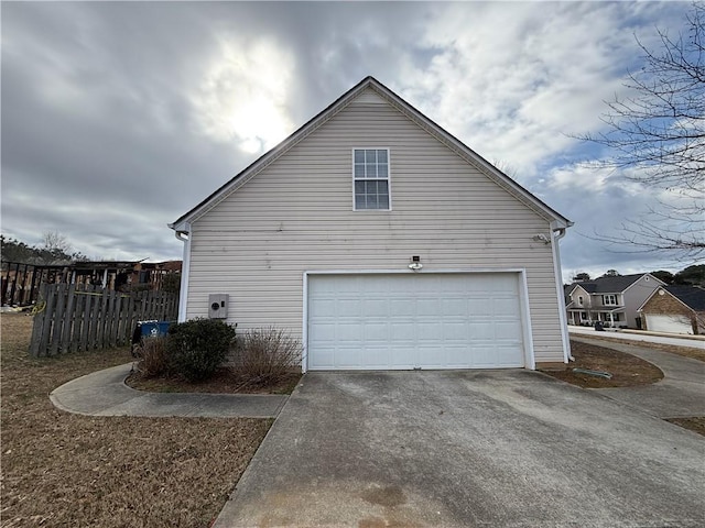 view of side of home with a garage, driveway, and fence