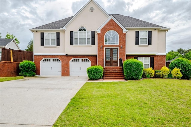 raised ranch with concrete driveway, an attached garage, stucco siding, french doors, and brick siding