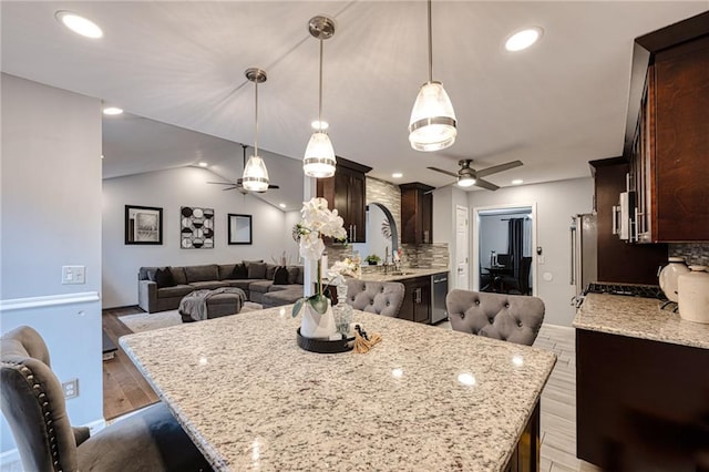 kitchen featuring ceiling fan, dark brown cabinets, and open floor plan