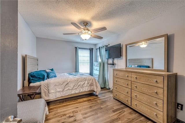 bedroom with a textured ceiling, a ceiling fan, and light wood finished floors