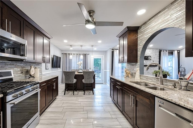 kitchen with backsplash, a sink, ceiling fan, and appliances with stainless steel finishes