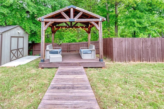 view of yard with an outbuilding, a fenced backyard, a storage shed, a deck, and a gazebo