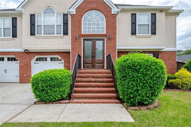 view of front of property with stucco siding, driveway, french doors, and brick siding