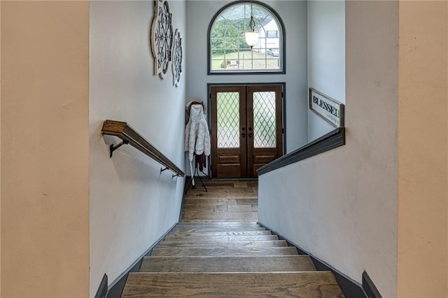 entrance foyer featuring stairs, wood finished floors, and french doors