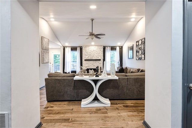 living room with visible vents, vaulted ceiling, a fireplace, wood finished floors, and a ceiling fan