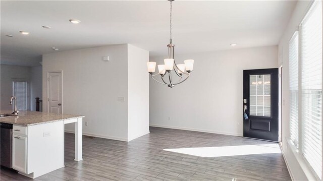 kitchen featuring hardwood / wood-style floors, a kitchen island with sink, a breakfast bar area, pendant lighting, and sink