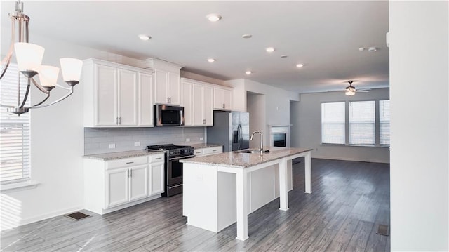 kitchen featuring stainless steel appliances, white cabinetry, sink, and a kitchen island with sink