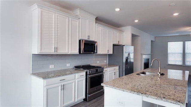 kitchen with stainless steel appliances, white cabinetry, a kitchen island with sink, and decorative backsplash