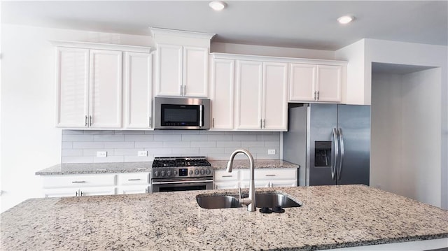 kitchen featuring appliances with stainless steel finishes, white cabinetry, backsplash, and sink