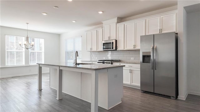 kitchen featuring appliances with stainless steel finishes, white cabinets, sink, and a center island with sink