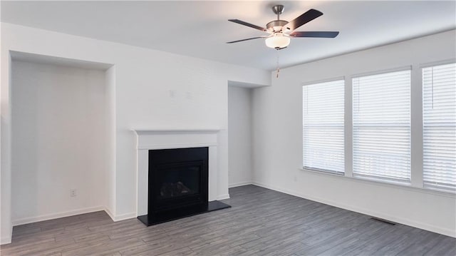 unfurnished living room featuring ceiling fan, a wealth of natural light, and wood-type flooring