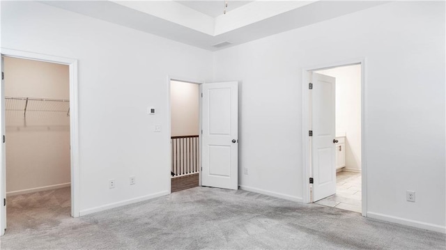 unfurnished bedroom featuring light colored carpet, a closet, and a spacious closet