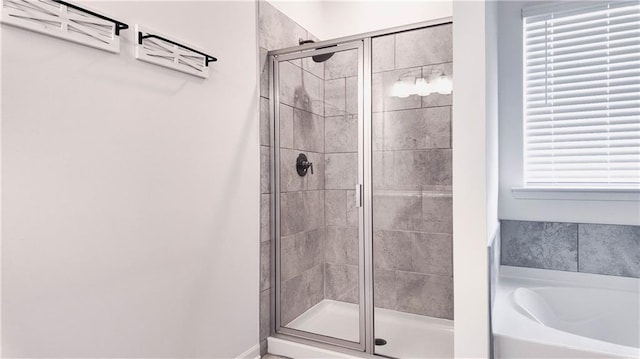 bathroom with a wealth of natural light and shower with separate bathtub