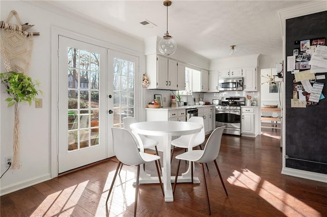 dining space with crown molding, dark hardwood / wood-style flooring, and french doors