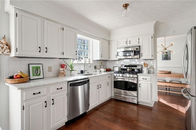 kitchen with appliances with stainless steel finishes, dark hardwood / wood-style floors, white cabinetry, sink, and crown molding