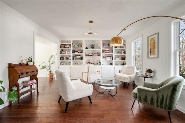 living area with an inviting chandelier, crown molding, built in features, and dark hardwood / wood-style floors