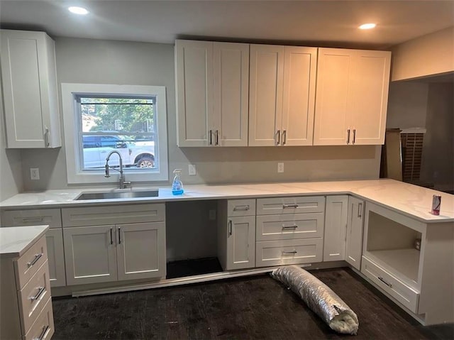 kitchen with kitchen peninsula, sink, dark wood-type flooring, and white cabinets