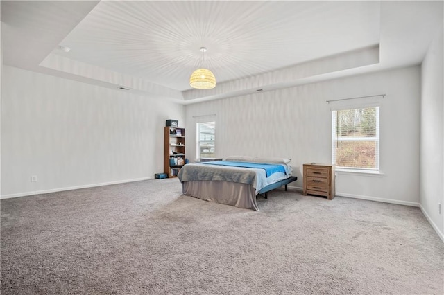 bedroom featuring baseboards, carpet floors, a raised ceiling, and multiple windows