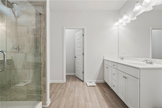 full bath with wood finished floors, a sink, a shower stall, and double vanity