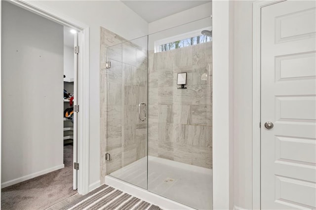 bathroom featuring a shower stall, a spacious closet, and baseboards