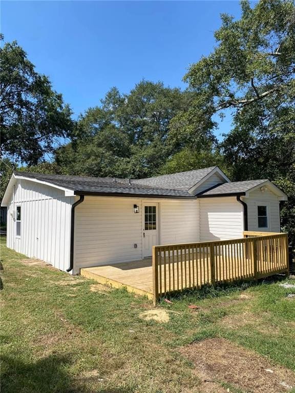 back of property with a wooden deck and a lawn