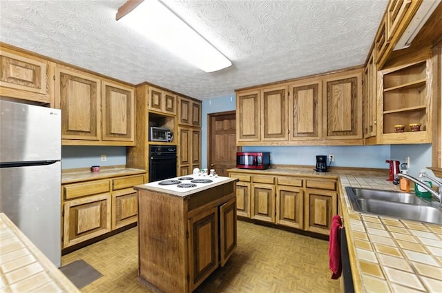 kitchen featuring open shelves, appliances with stainless steel finishes, a sink, and tile counters