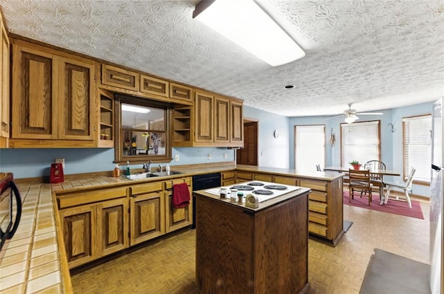 kitchen with tile countertops, a kitchen island, a peninsula, open shelves, and a sink