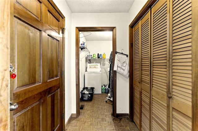 hallway featuring washer / dryer, a textured ceiling, and baseboards