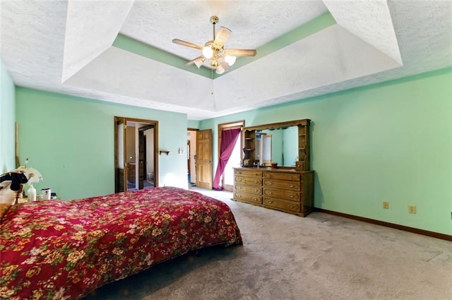 bedroom featuring a textured ceiling, carpet floors, and a tray ceiling