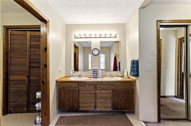 bathroom featuring double vanity, a textured ceiling, and a sink