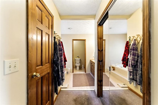 hallway with a textured ceiling and carpet flooring