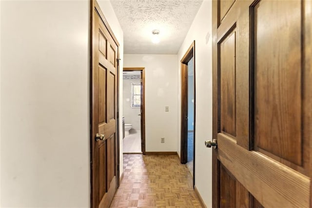 hall with baseboards and a textured ceiling