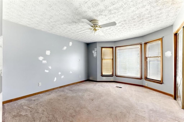 empty room featuring carpet floors, ceiling fan, a textured ceiling, and baseboards