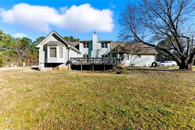 rear view of house with a chimney, a deck, and a lawn