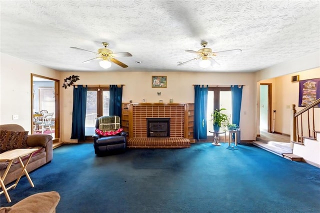 carpeted living area featuring ceiling fan, a textured ceiling, baseboards, and stairs