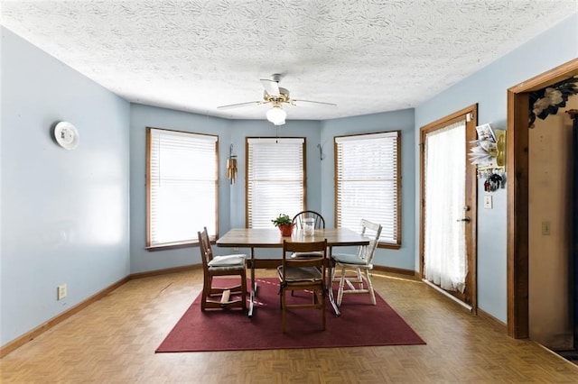 dining area featuring ceiling fan, baseboards, and a textured ceiling