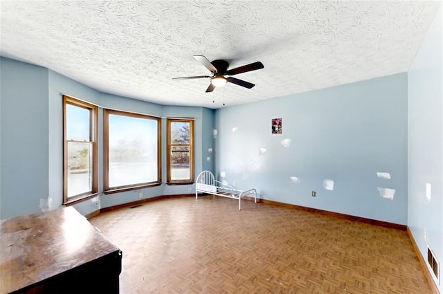 unfurnished room featuring visible vents, ceiling fan, a textured ceiling, and baseboards