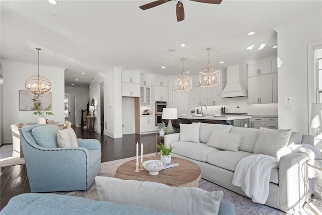 living room with ceiling fan with notable chandelier, recessed lighting, and dark wood-style flooring