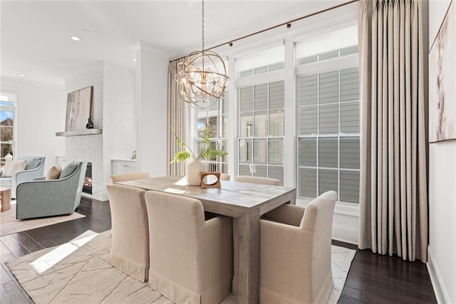 dining area featuring hardwood / wood-style flooring, a brick fireplace, recessed lighting, and a chandelier