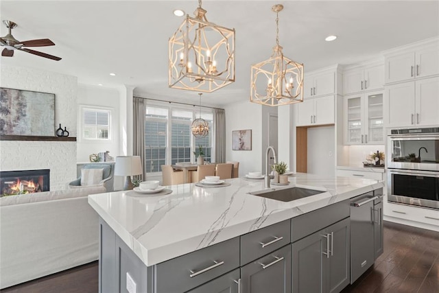 kitchen with a sink, double oven, a fireplace, and gray cabinets