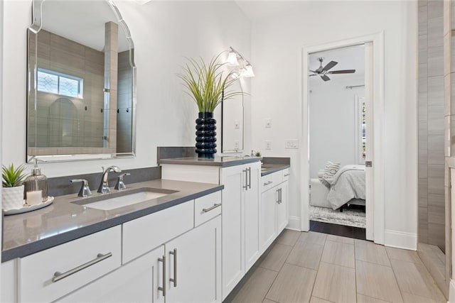 bathroom featuring tiled shower, two vanities, ceiling fan, and a sink