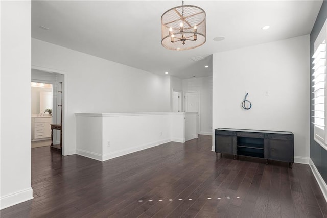 unfurnished living room with a chandelier, baseboards, and wood finished floors