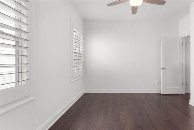 spare room with dark wood finished floors, plenty of natural light, a ceiling fan, and baseboards