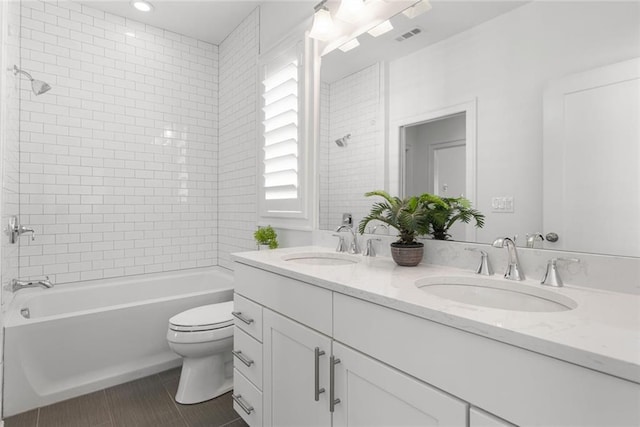 bathroom featuring a sink, toilet, double vanity, and shower / tub combination