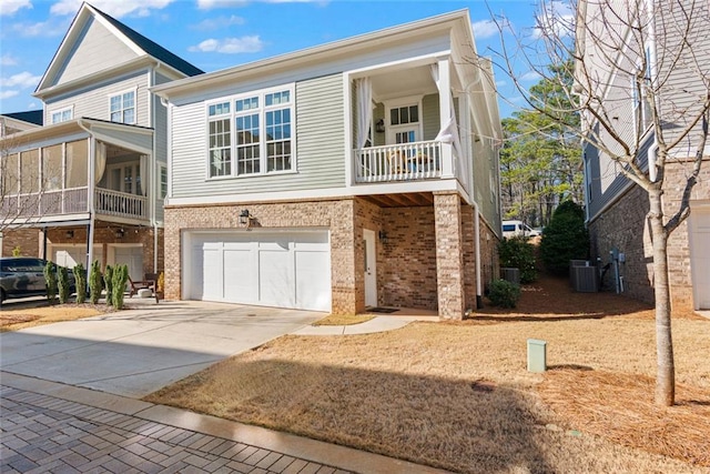 view of front facade with brick siding, central air condition unit, an attached garage, and concrete driveway