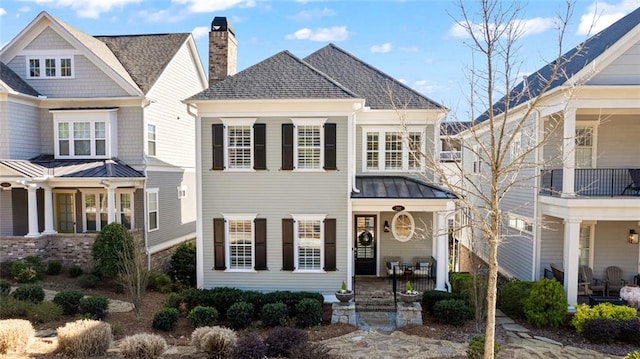 view of front of property with a standing seam roof, metal roof, a shingled roof, and a chimney